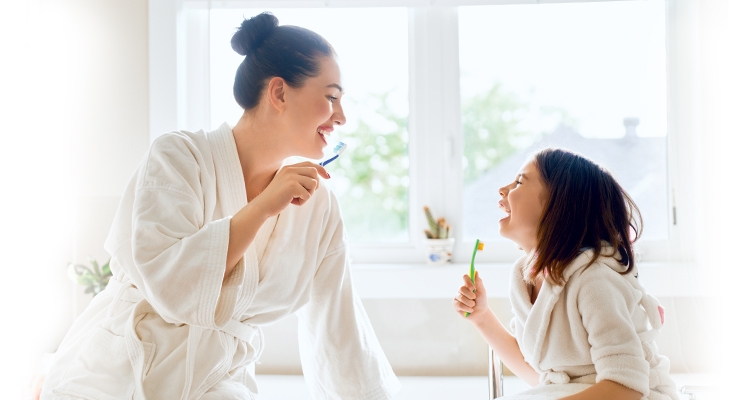 Mother and daughter brushing their teeth together with GLISTER oral care 1 